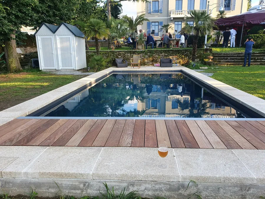 Après : la piscine rénovée, eau claire, caillebotis en bois et margelles neuves
